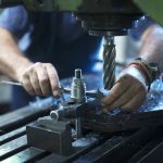 Worker operating industrial machine in metal workshop.