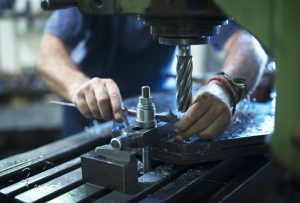 Worker operating industrial machine in metal workshop.